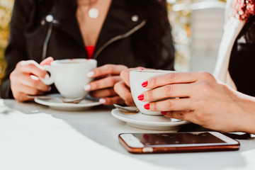 .A couple of beautiful women having a coffee together on a sunny spring morning on a terrace in Madrid. Urban lifestyle. Close up photography.