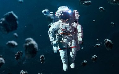 Astronaut at asteroid field. Science fiction wallpaper. Elements of this image furnished by NASA
