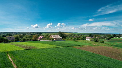 Fototapeta na wymiar Top view of rural landscape on sunny spring day. House and green field. Drone photography