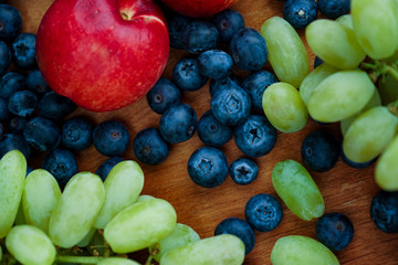 seasonal fruits. red nectarines, green grapes and blueberries on a light wooden background
