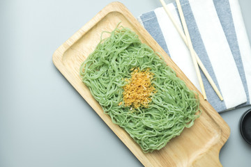 Green noodles with fried garlic on wooden tray