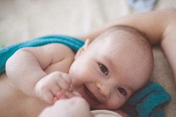 Happy laughing baby lying next to the mother, breastfeeding
