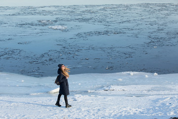 young woman walking on the frozen coast