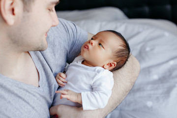 Closeup of young Caucasian father with newborn mixed race Asian Chinese baby. Male man parent...