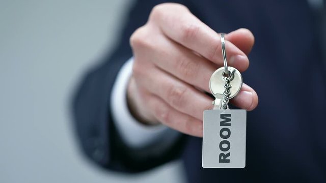 Room word on keychain in male hotel administrator hand, booking service, concept
