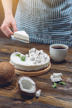 Confectioner holding a piece of coconut raw cake with white pulp. Healthy vegan dessert. Gluten and sugar free food