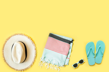 Obraz na płótnie Canvas Beach female accessories, straw beach hat, towel, sunglasses on yellow. Space for text. Summer tropical vacation.