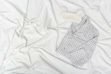 Warm grey pajamas and fluffy eye mask on white sheet. Cozy accessories for quiet sleep. Sleepwear...