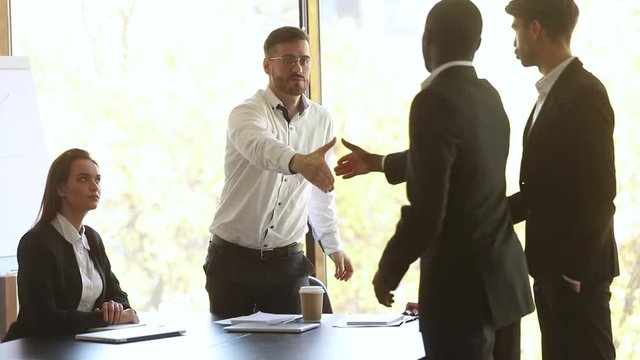 Company representative welcoming handshaking diverse partners coming at meeting