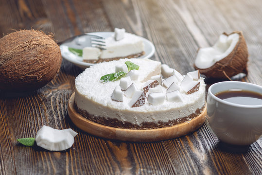 Raw coconut cake decorated with white coconut pulp and mint on a wooden background. Healthy vegan dessert.