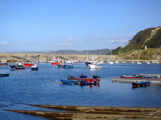 Obraz premium Colorful boats anchored in the port of Cudillero under the lighthouse.