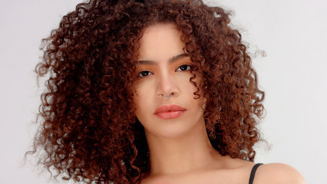 hair blowing closeup portrait of mixed race model with freckles watching to the camera. Piersing in nose