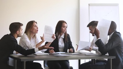 Angry diverse team colleagues argue over paperwork during company meeting