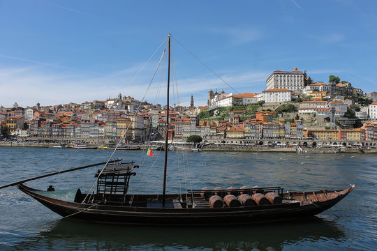 Brown sail boat with wine barrels in the Douro river in Porto, Portugal.