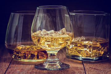 glass of whiskey with ice on a wooden background