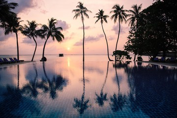 The beach at sunsrise on tropical island with palm trees.