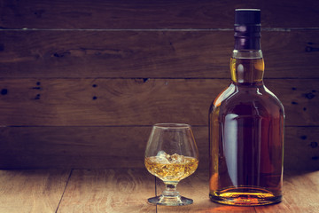 bottle and glass of whiskey  on a wooden background made with vintage tones