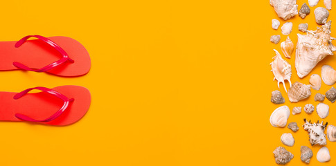 Summer beach sea accessories. Coral flip flops, shells, starfish on yellow background top view flat lay copy space. Summer background. Holiday vacation travel concept.