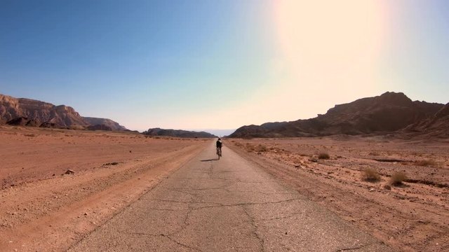 Cyclist riding on an empty Single Desert road, Follow footage.