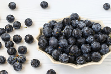 Berries blackthorn are located in a plate on a white background