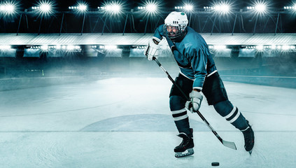 Plakat Ice Hockey player athlete in the helmet and gloves on stadium with stick. Action shot. Sport concept.
