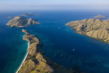 Naklejka premium Seen from a bird's eye view, the blue Pacific Ocean surrounds the rugged island of Komodo in Indonesia. This tropical area is known for its marine biodiversity as well as its dragons.