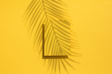 Tropical palm leaf shadow on a yellow blank label. Exotic summer background.