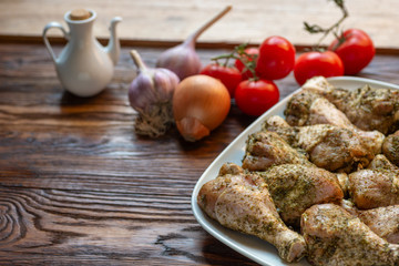 Raw chicken legs with herbs and spices on white dish.
