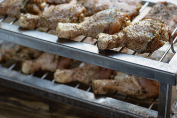 Marinade chicken legs on metal grill.