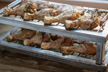 Marinade chicken legs on metal grill.