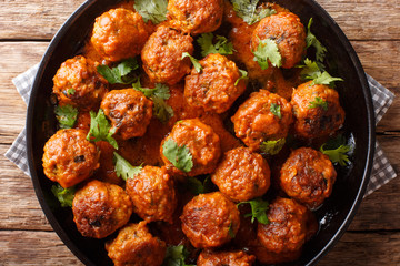 Asian chicken meatballs in a creamy coconut sauce with red curry closeup on a plate. horizontal top view