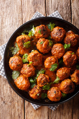 Asian chicken meatballs in a creamy coconut sauce with red curry closeup on a plate. Vertical top view