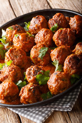 spicy chicken Indonesian Meatballs come complete in a creamy coconut curry sauce close-up on a plate. Vertical