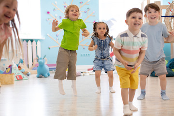 Group of happy kids playing and jumping in daycare