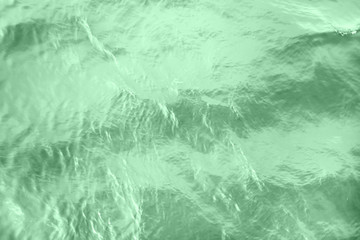 Closeup of calm river water surface with water splashes in neo mint color. Ideal river, sea and ocean texture. Trendy fresh abstract nature background. Color of the year 2020