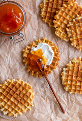Belgian waffles with jam on a baking paper, flat lay, top view. Delicious breakfast or lunch with homemade Belgian waffles.