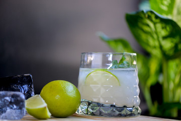 glass of water with lemon and lime on wooden table