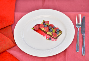 dessert cake with berries in a plate on a red background
