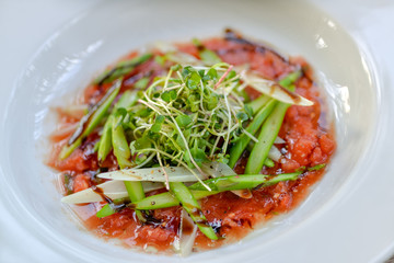 asparagus with tomato sauce on a white plate