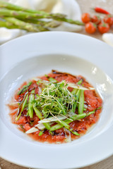 asparagus with tomato sauce on a white plate