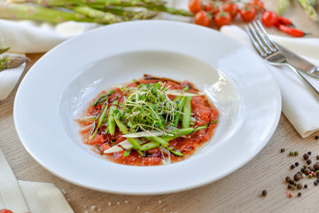 asparagus with tomato sauce on a white plate