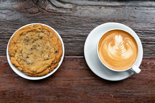 Big Chocolate Chip Cookie on a Plate with a Latte on a Wood Table