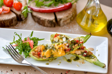 baked zucchini with cheese and vegetables on a rectangular plate