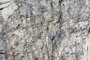 Close up macro view of cracked stone surface gray color. Detailed nature background or pattern texture taken in natural environment. Weathered many years, inimitable, unique effect to textured design