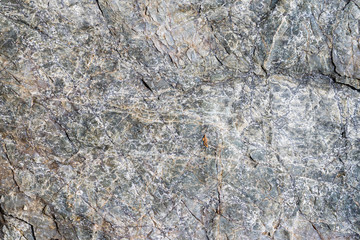 Closeup macro view of rough stone surface gray color. Detailed nature background or pattern texture taken in natural environment. Weathered many years, inimitable and unique effect to textured design