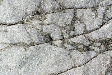 Close-up macro view of cracked stone surface gray color. Detailed nature background or pattern texture taken in natural environment. Weathered many years, inimitable and unique effect textured design.