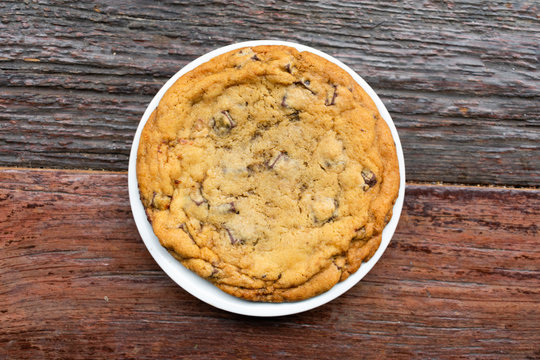 Big Chocolate Chip Cookie on a White Plate on a Wood Table