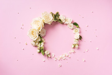 Flowers composition. Wreath made of white roses and rose petals on pink background. Flat lay, top...