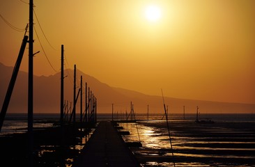 Fototapeta na wymiar 海に続く道がある海岸の日没風景