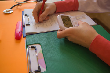 Medicine doctor's working table. Healthcare concept. Female medical doctor writing something sitting at her office